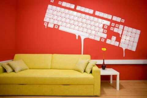 Red color wall with keyboard painting and yellow sofa with white table